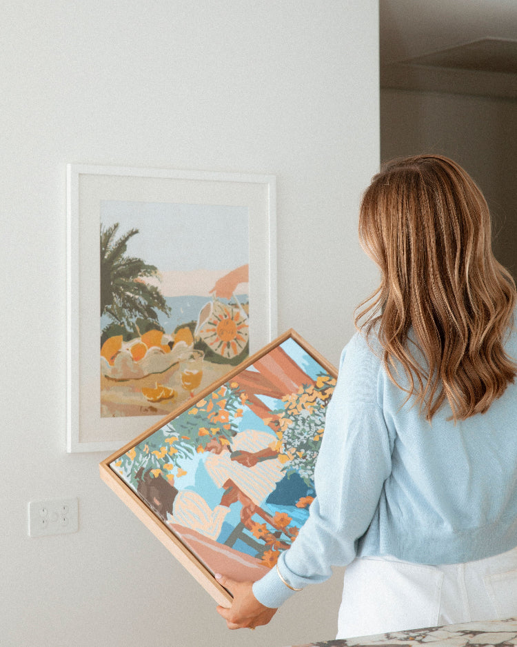 Paint Like Frida Sun & Lemons Big Rolled Canvas in white frame hanging on the wall and Tea in the Afternoon Big Framed Canvas