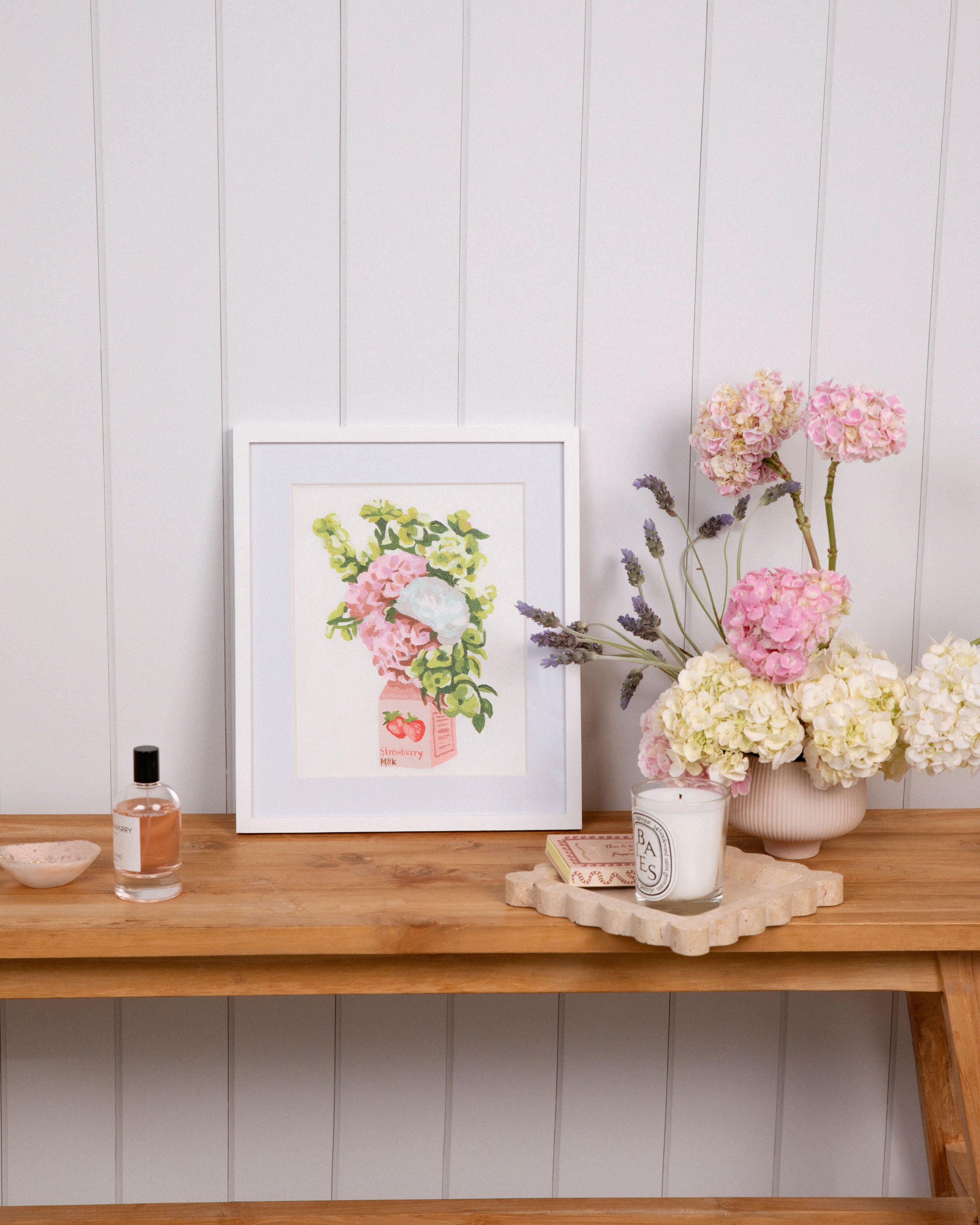 Strawberry Milk mini rolled canvas framed in a white minimalist frame on top of a table next to a flower vase