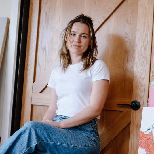 Artist Jade Cummings sitting against a timber door head shot