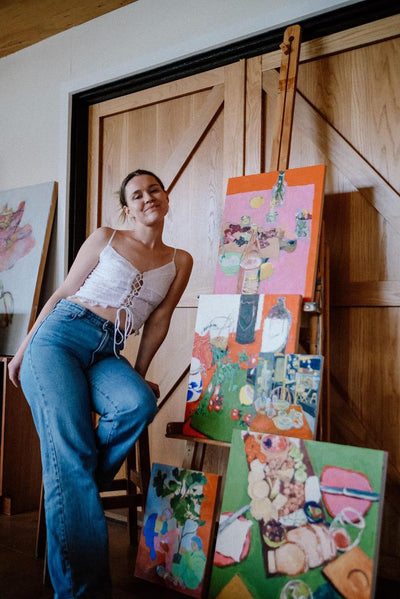 Artist Jade CUmmings next to a collection of her art