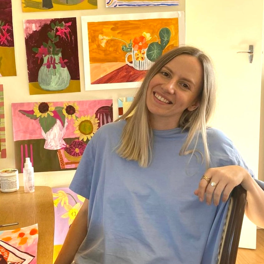 Artist Crystal Knight sitting in her home studio with her art behind her