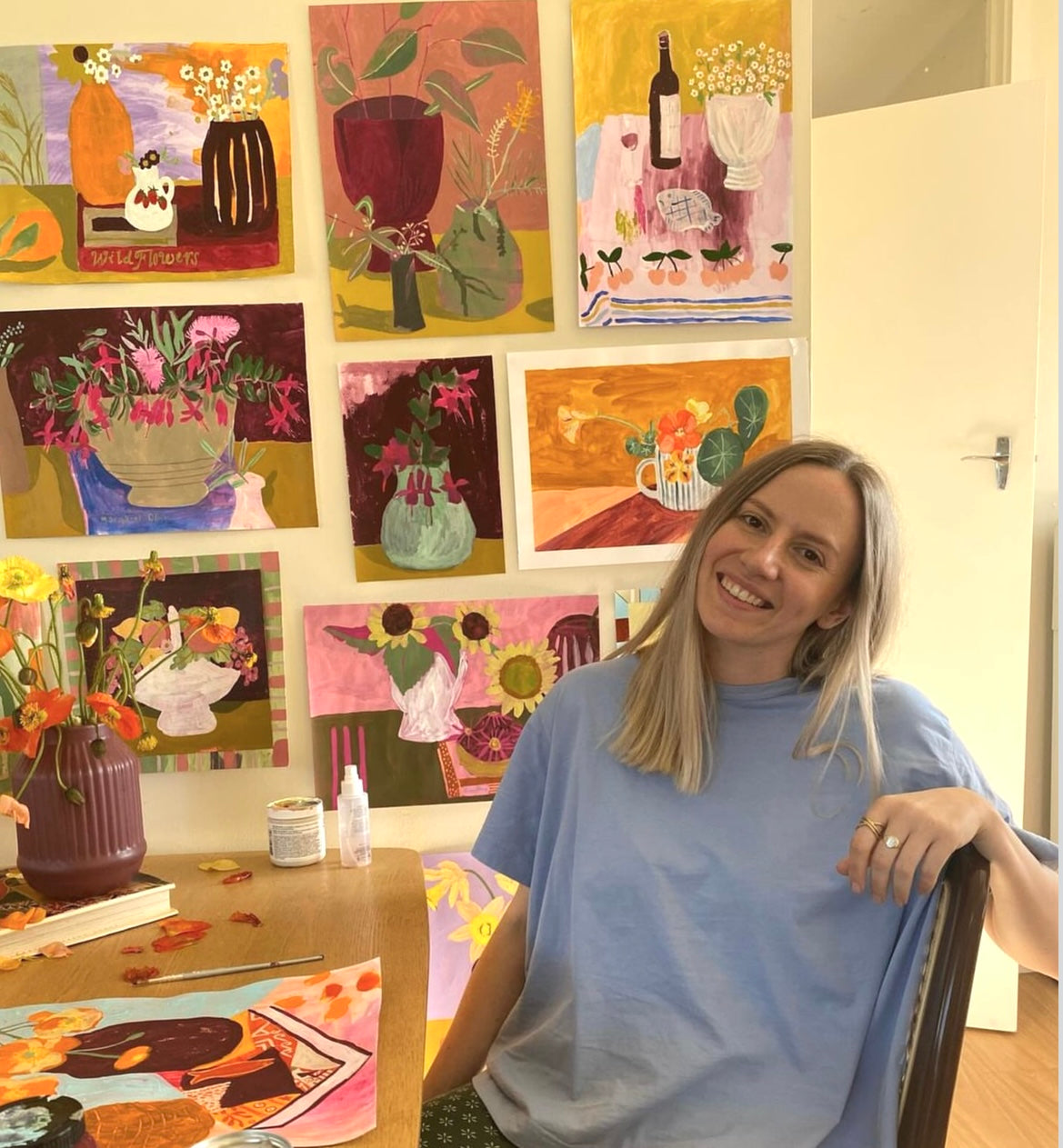 Artist Crystal KNight Sitting in her studio with her art behind her