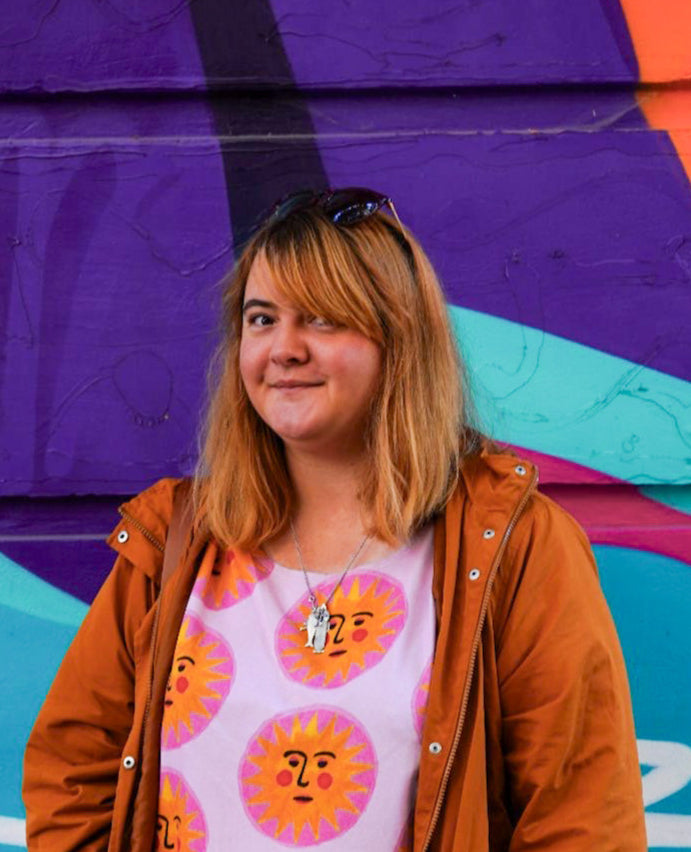 Ekaterina HEadshot standing in front of a colourful mural