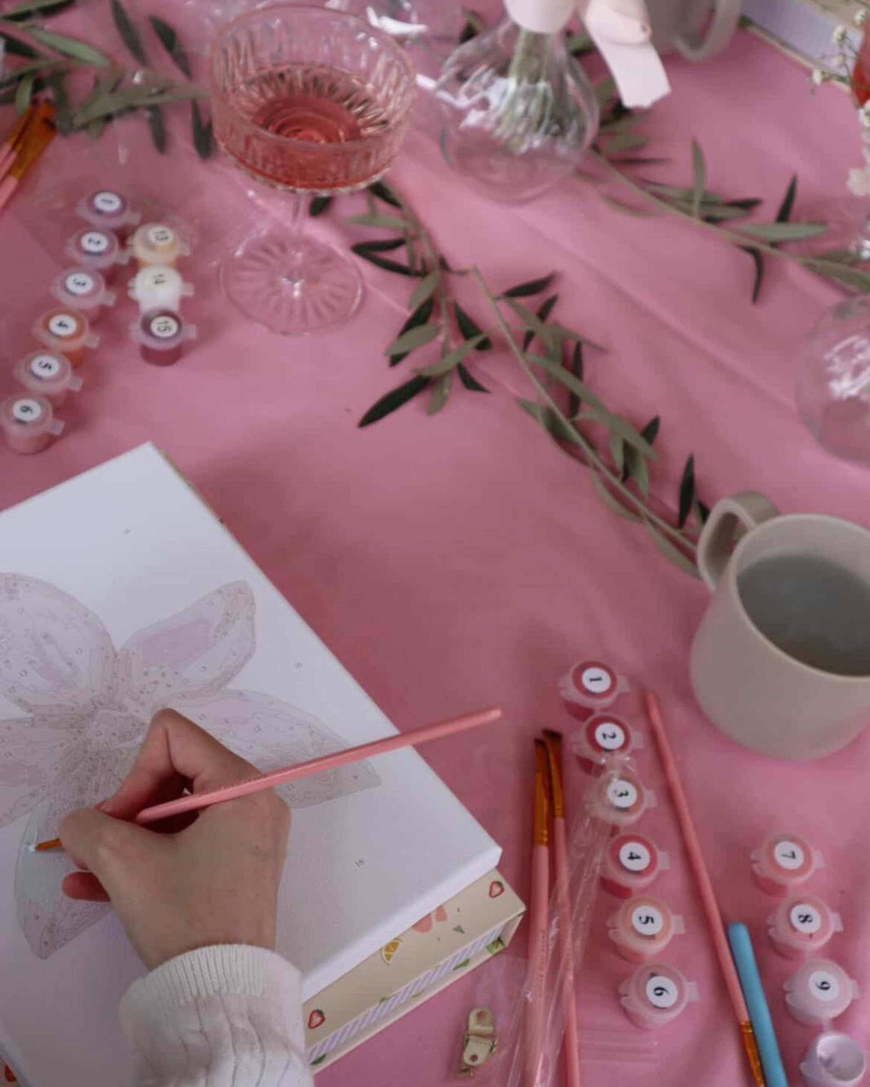 Beginner-friendly orchid paint-by-numbers kit in progress, with soft pink paints, brushes, and creative setup for a fun painting experience.